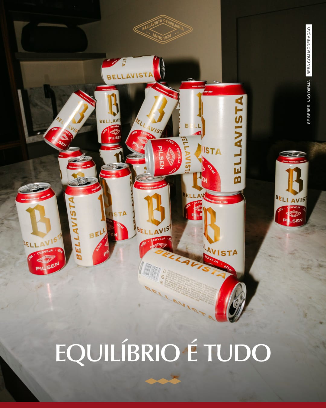 Treze latas da cerveja Bellavista Pilsen dispostas sobre bancada de mármore em ambiente interno, com tagline "Equilíbrio é tudo" em destaque