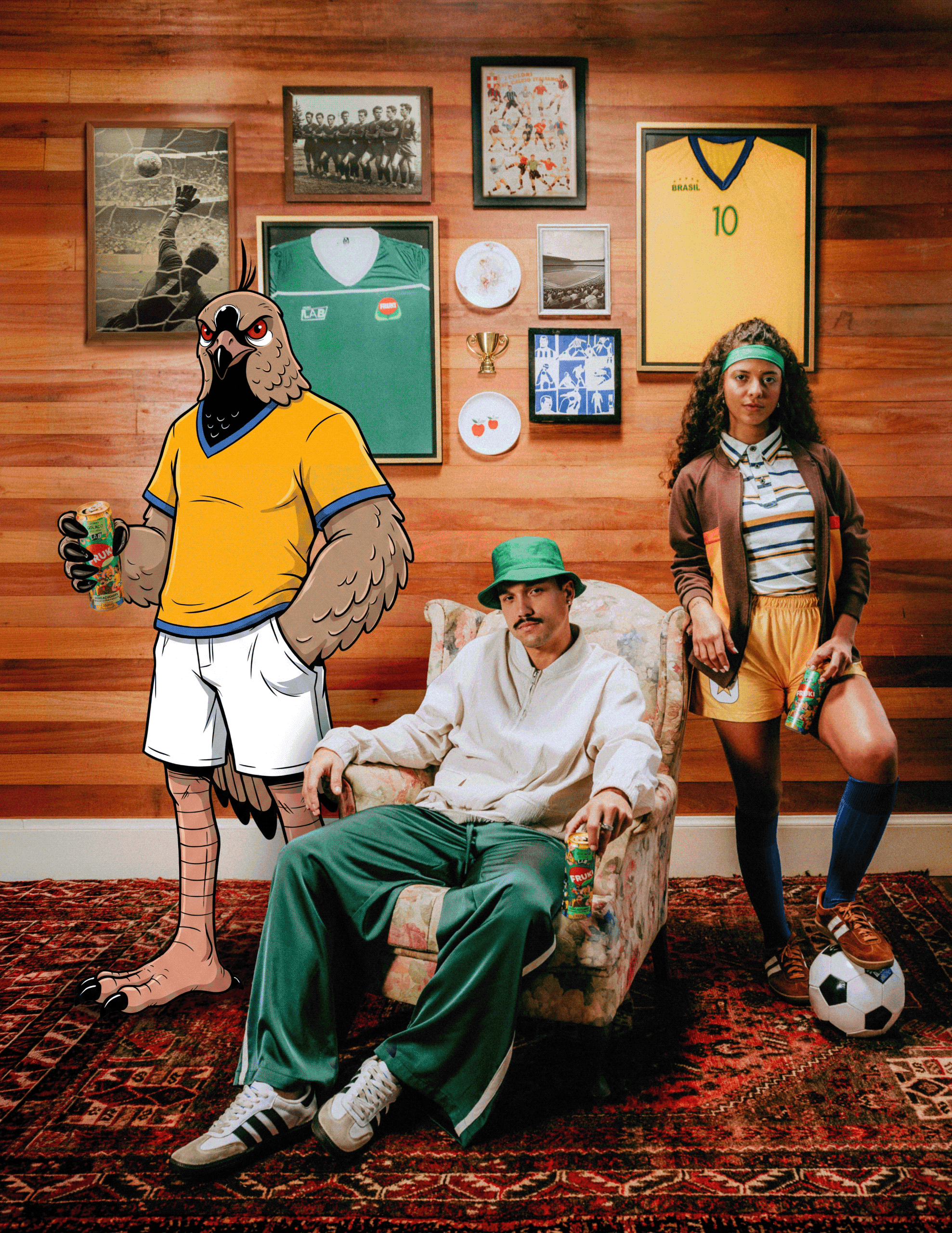 Peça-chave da campanha Fruki Pipoca: mascote quero-quero ilustrada com camisa amarela da seleção segurando uma lata Fruki, ao lado de dois modelos reais sentados e em pé em ambiente decorado com camisas de time emolduradas, troféu e fotos antigas de futebol na parede