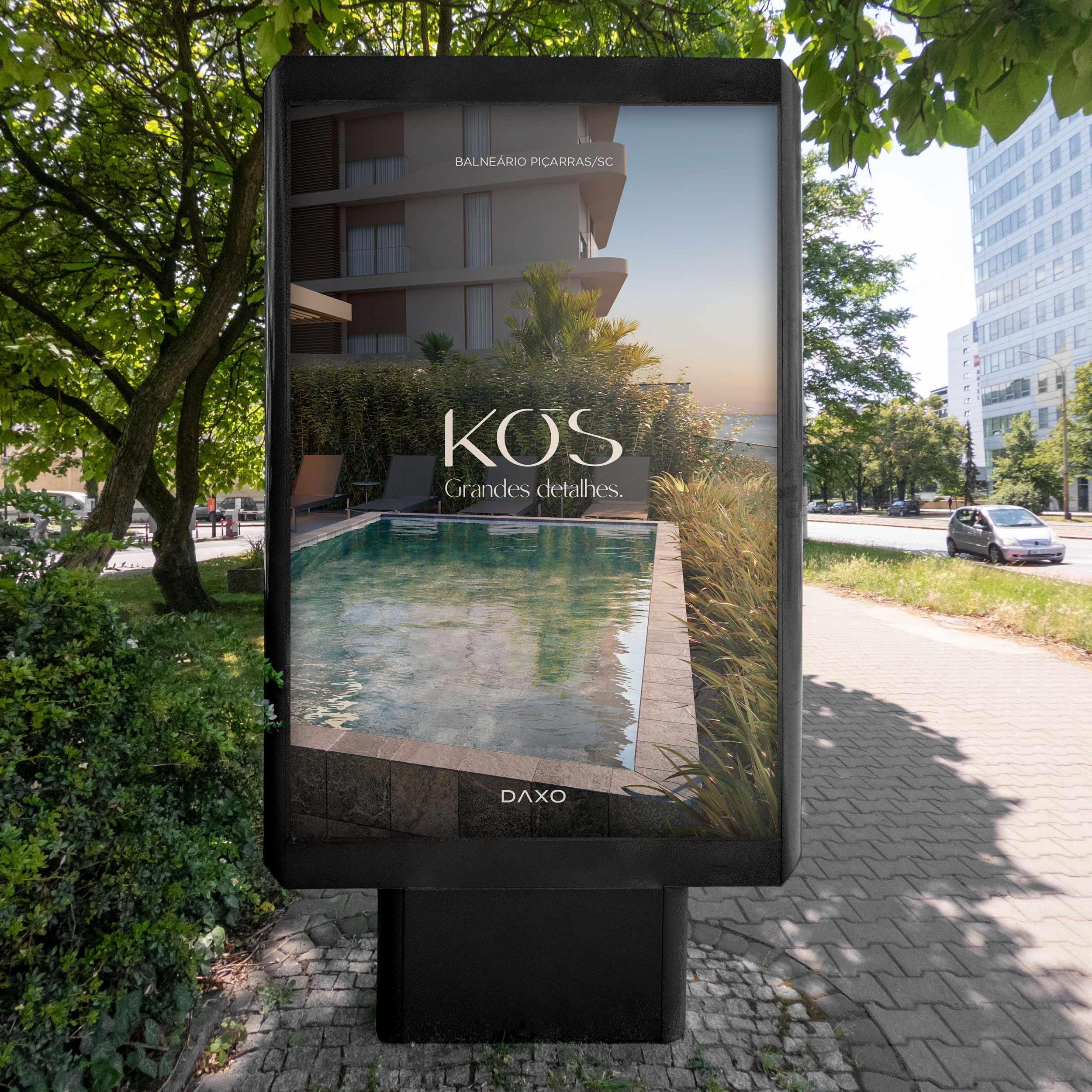 Mockup de totem de mobiliário urbano com anúncio do Kós mostrando a piscina do rooftop ao entardecer, texto "Grandes detalhes." — peça do lado direito do díptico publicitário